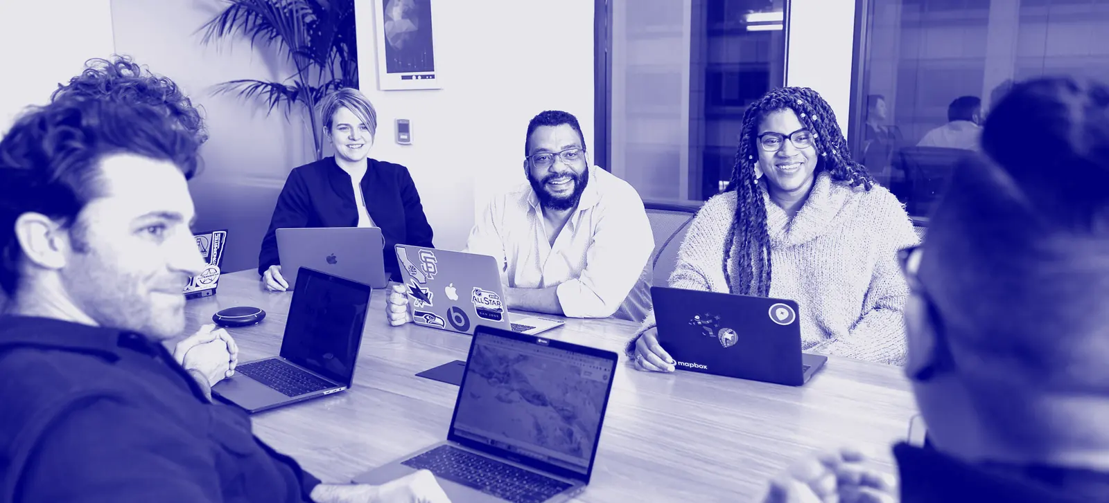 Equipo en una reunión de trabajo con portátiles, sonriendo